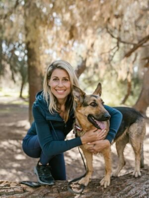 A Woman in Blue Jacket Smiling while Embracing Her Dog